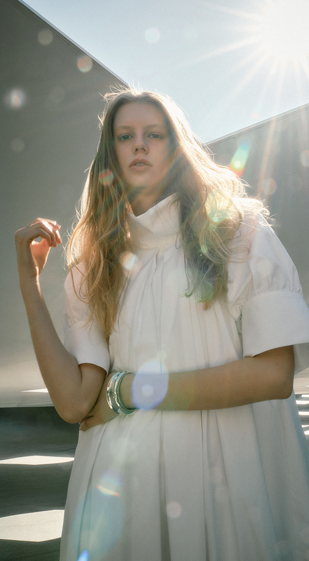 ドミノ型のオブジェの間に立つ黄色いドレスワンピースの女性